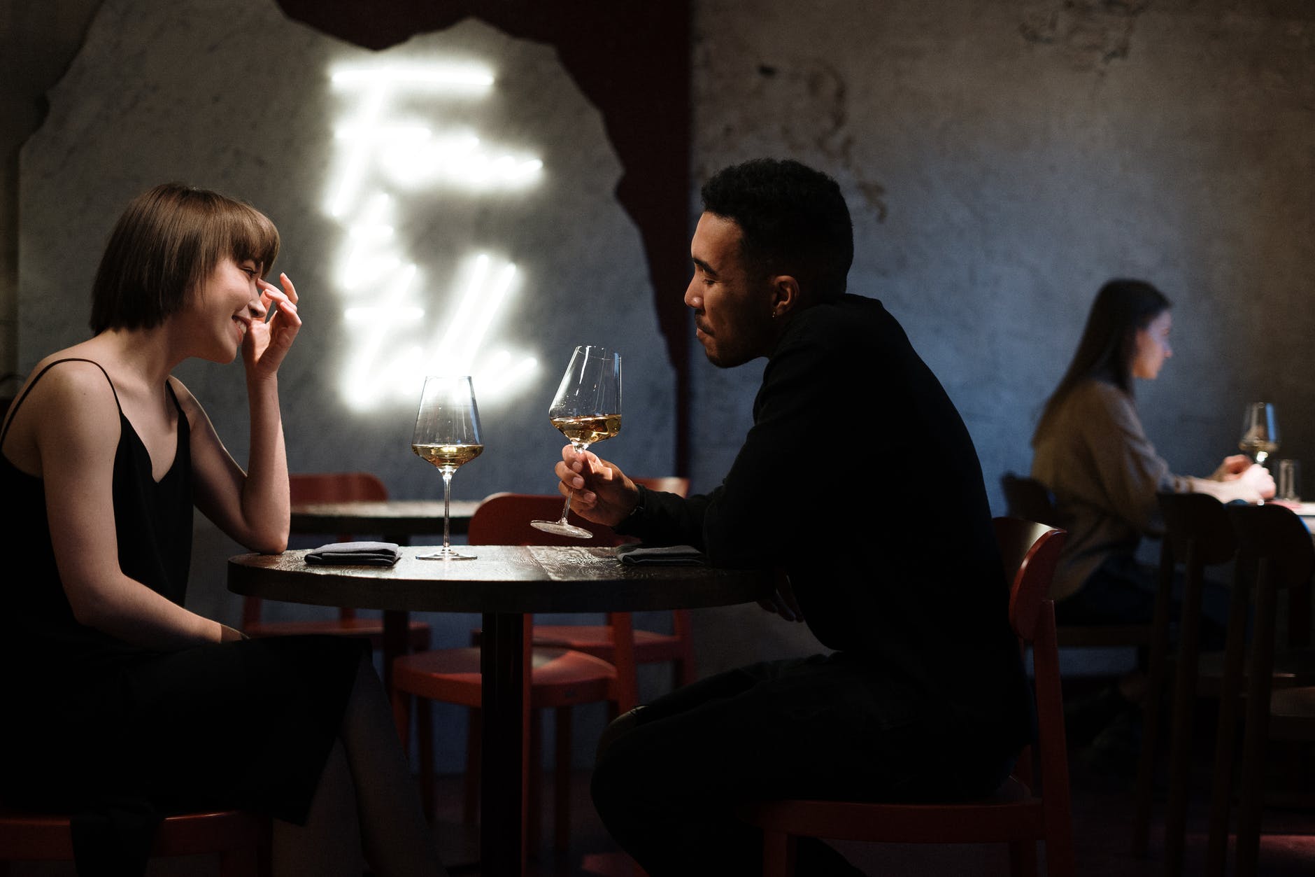 Interracial couple on a dinner date drinking wine at a table